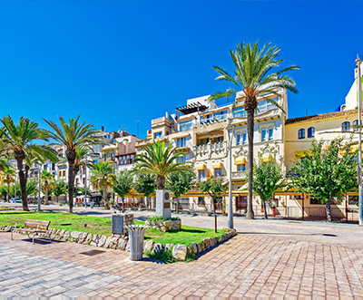scenic view of a palm tree lined street with colorful buildings and clear blue sky suitable for a relaxing vacation near the beach with 14 vibrant elements