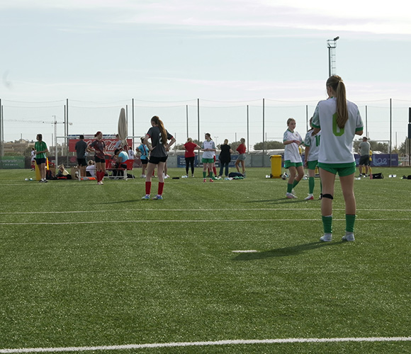 female soccer players on a training field with green grass and sports equipment in the background several players preparing for the game while others practice skills and drills 4 soccer players on field